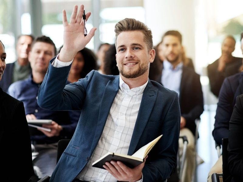 Man in audience with hand raised