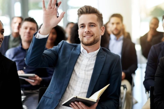 Man in audience with hand raised